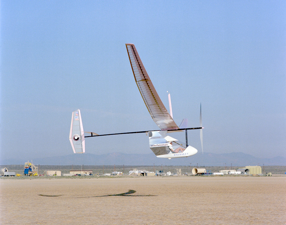 An aircraft flying in the air shown from outside, which is powered by a bicycle-type drive mechanism.