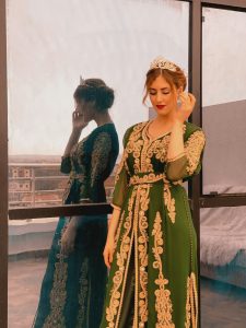 woman wearing green dress with gold detailing and a gold tiara