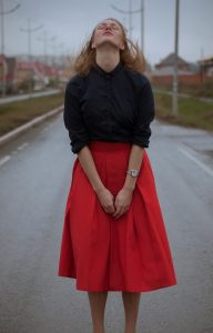 woman wearing a black sweater and a red skirt