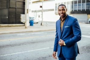 Man wearing an orange button up under a blue suit jacket