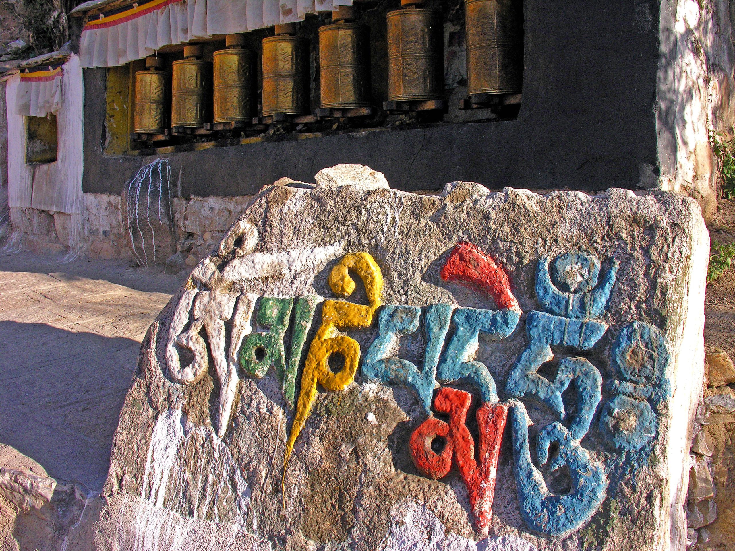 large stone (called a mani stone) with colorful Tibetan text inscribed