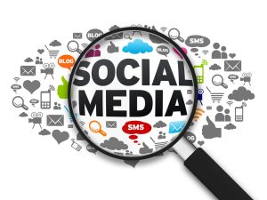 Magnifying glass on top of image that says "social media" and is surrounded by social media icons.