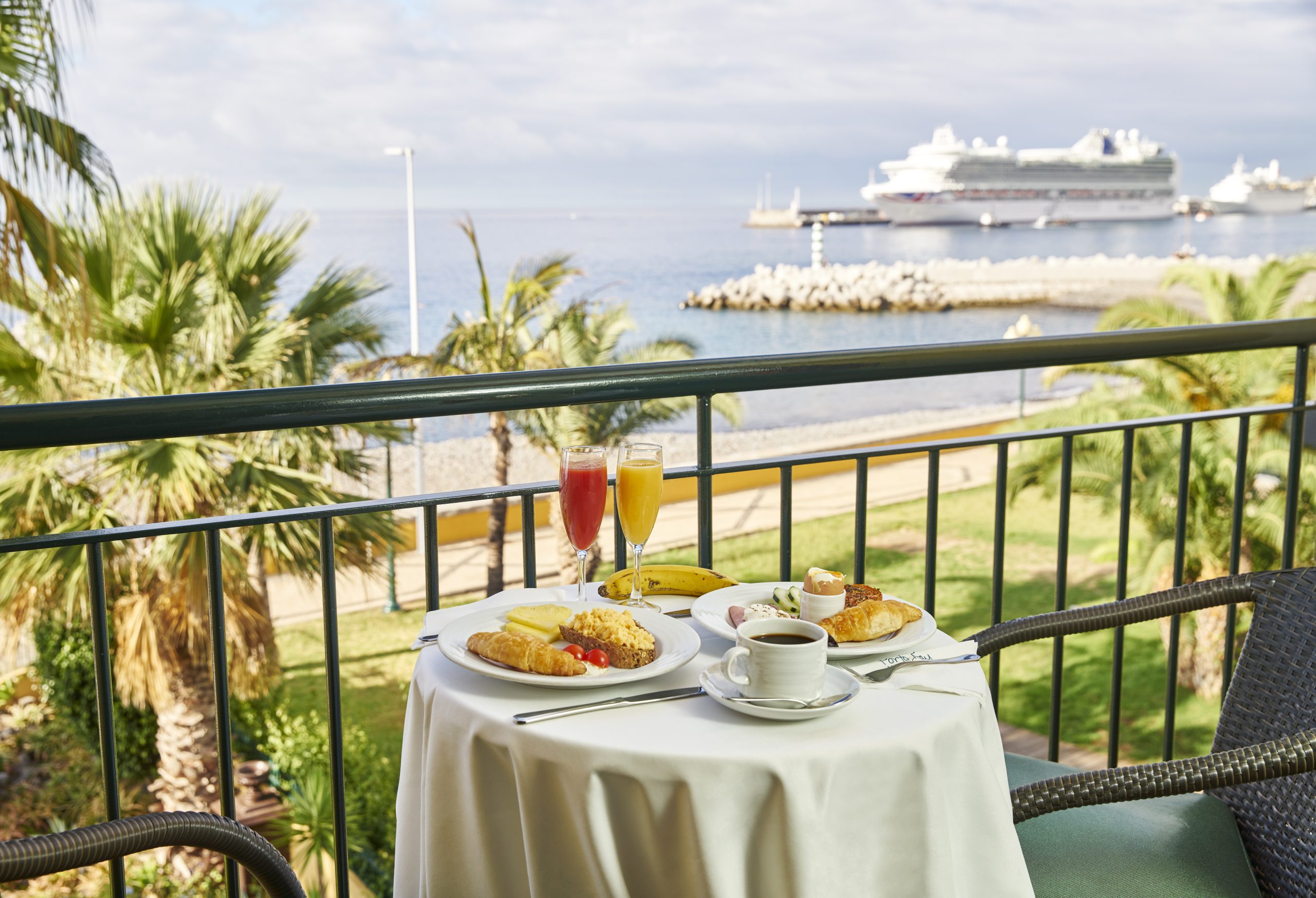 A table for two on a balcony overlooking a tropical, beach setting