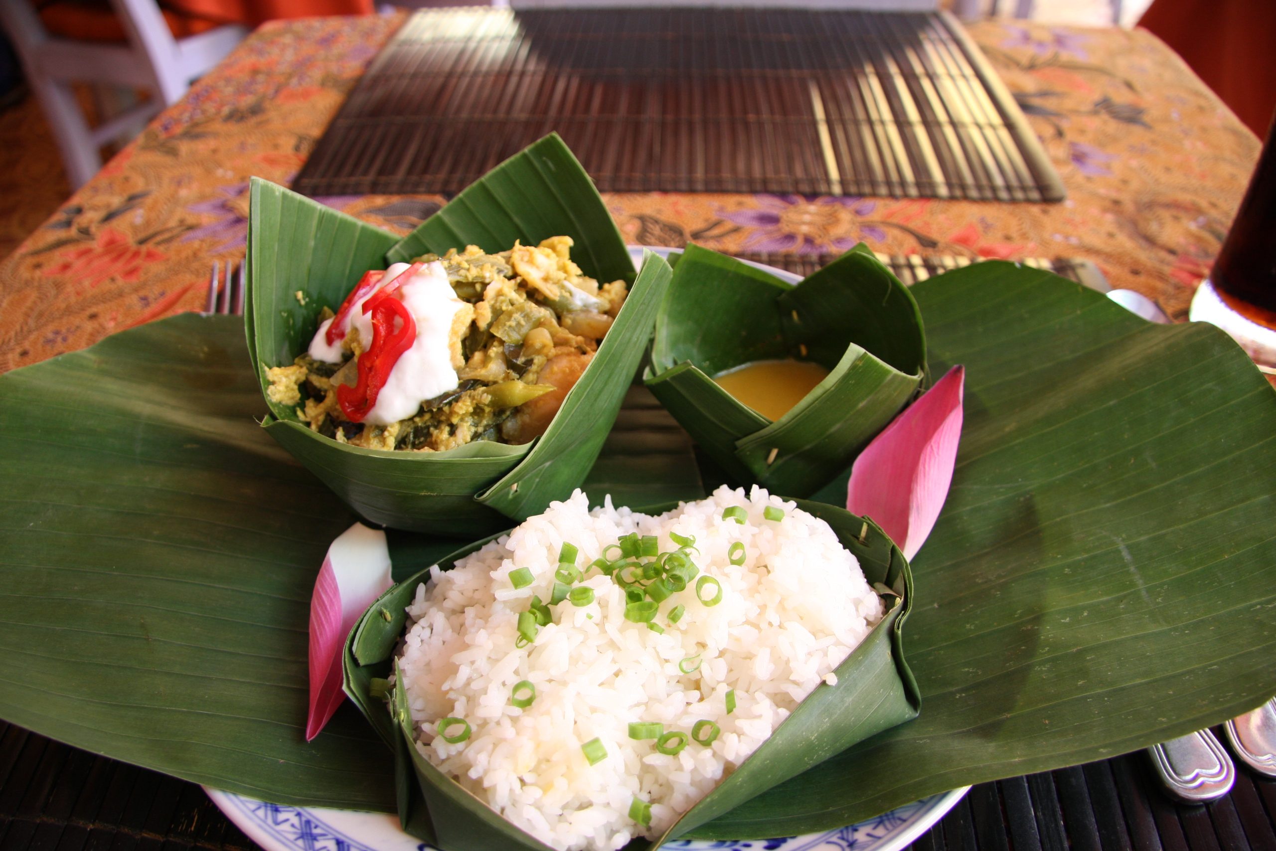 Fish Amok, white rice, and a sauce served in bowls made from leaves