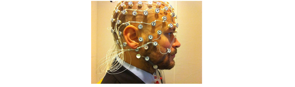 Photograph of a man with EEG recording electrodes placed on the scalp. Details in caption and text.