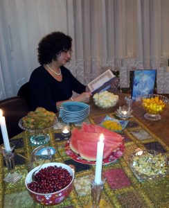 a lady in black shirt sitting by a table decorated for yalda night